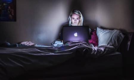 young girl watching laptop in a dark room